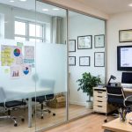 Modern üvegfalú iroda belső tér üzleti grafikonokkal, poszt-it jegyzetekkel és elemzésekkel a falon